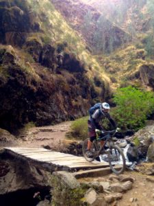 Biker crossing bridge in cusco peru on bike tour peru