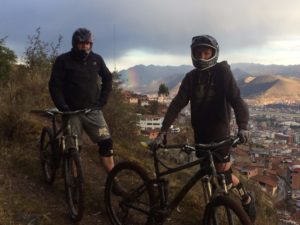 Cusco Biking tour half day bike ride with two bikers overlooking city with rainbow