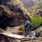 Biker crossing bridge in cusco peru on bike tour peru