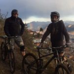 Cusco Biking tour half day bike ride with two bikers overlooking city with rainbow